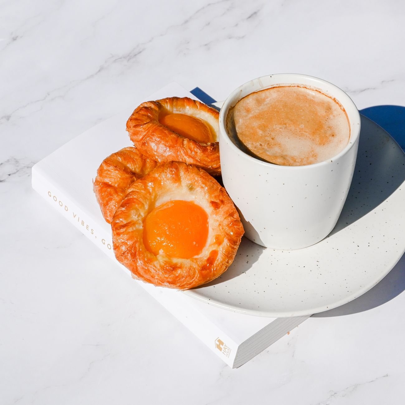 A top view of fresh pastries with a cup of coffee on marble, perfect for a cozy breakfast.